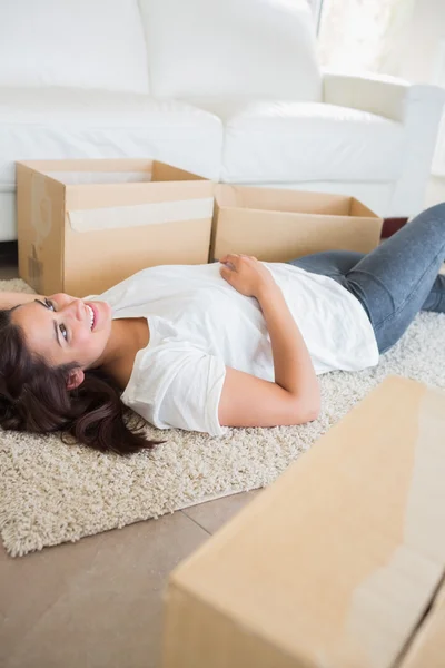 Donna sdraiata sul tappeto accanto a scatole in movimento — Foto Stock