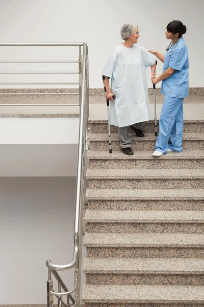 Oudere patiënt wordt geholpen door verpleegkundige naar beneden trappen — Stockfoto