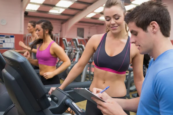 Trainer helping a woman in a gym — Stock Photo, Image