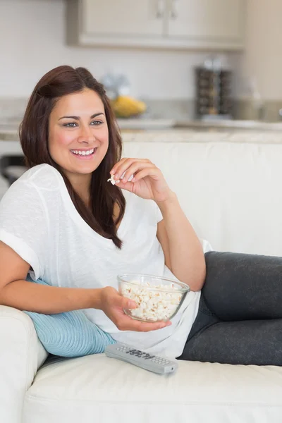 Kvinna äta popcorn medan du kopplar av i soffan — Stockfoto