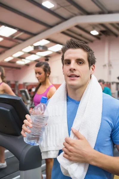 Uomo sorridente e acqua potabile in palestra — Foto Stock