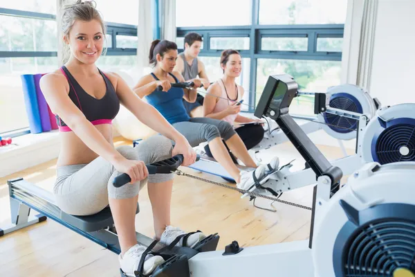 Lachende vrouw op roei-machine met anderen — Stockfoto