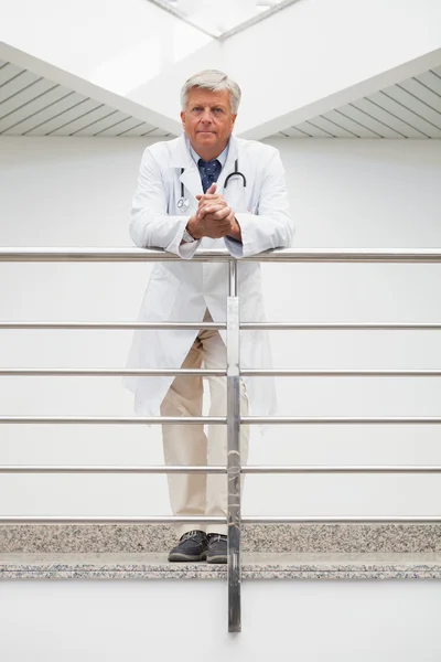 Doctor leaning on rail in hospital corridor — Stock Photo, Image