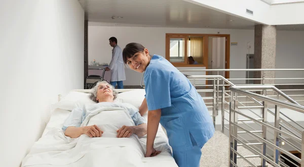 Verpleegkundige glimlachend naast een oudere dame — Stockfoto