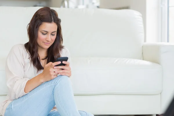 Brunette texting met mobiele telefoon op de verdieping — Stockfoto