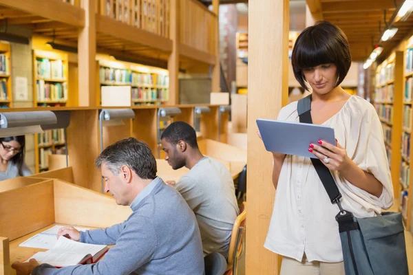 Woman looking at her tablet pc while other are reading Stock Image