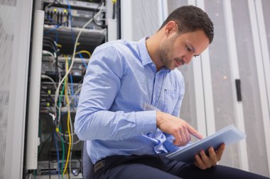 Man using tablet pc beside servers clipart
