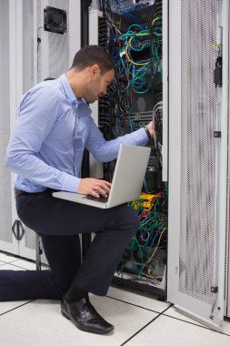 Man fixing wires while doing maintenance in data center clipart