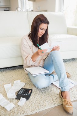 Woman checking bills in the living room clipart