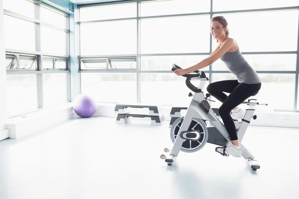 Donna felice in sella a una cyclette — Foto Stock