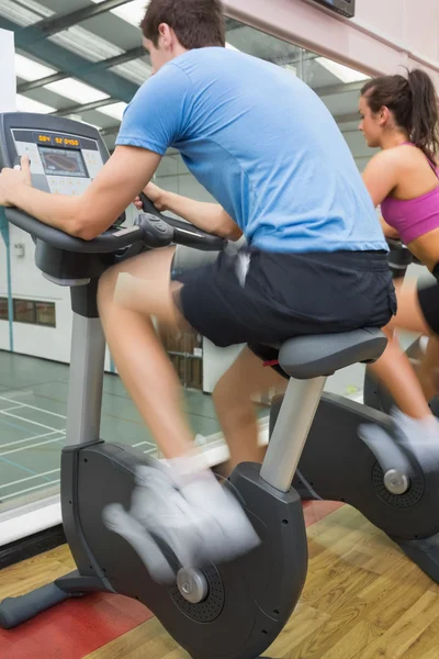 Man and woman riding on an exercise bike — Stock Photo, Image