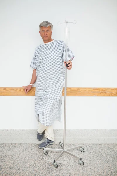 Patient holding IV drip leaning against wall — Stock Photo, Image