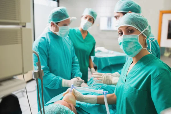 Медсестра держит кислородную маску на пациенте, когда смотрит на камеру — стоковое фото