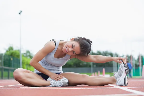 Smiling woman stretching on a track — Stock Photo, Image