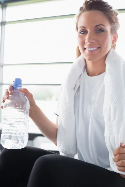 Mujer con toalla alrededor del cuello bebiendo agua — Foto de Stock