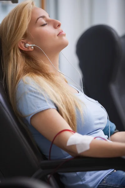 Žena darování krve a poslechu hudby zařízení — Stock fotografie