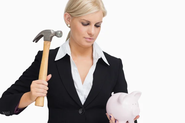 Serious businesswoman holding a piggy-bank and hammer — Stock Photo, Image