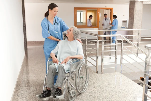 Krankenschwester wacht über alte Frauen im Rollstuhl — Stockfoto