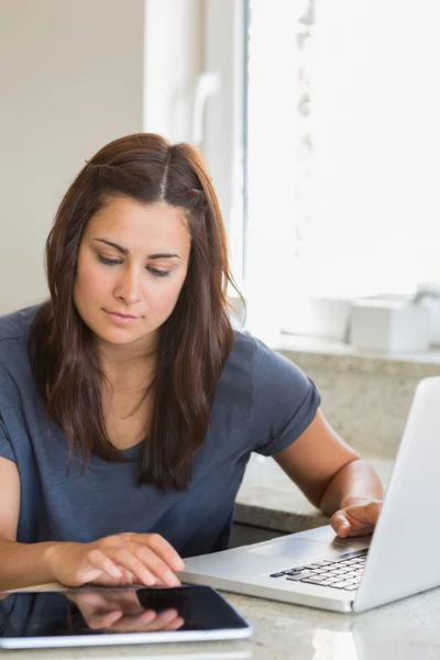 Brunett skriver på TabletPC och laptop — Stockfoto