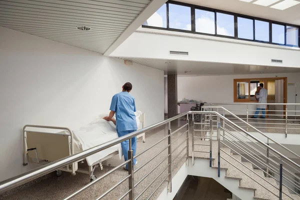 Sjuksköterska tenderar att patienten i sängen i korridoren — Stockfoto
