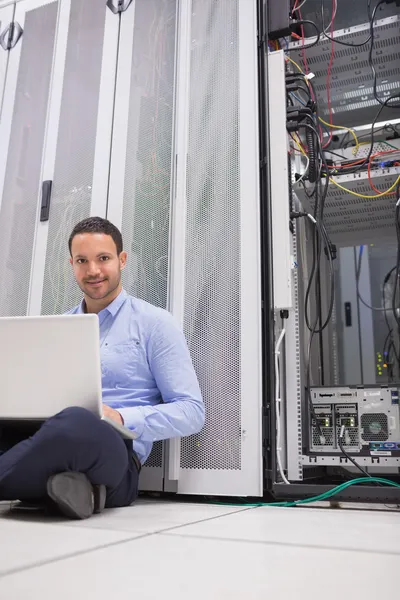 Man zit op de vloer met behulp van laptop te controleren van servers — Stockfoto