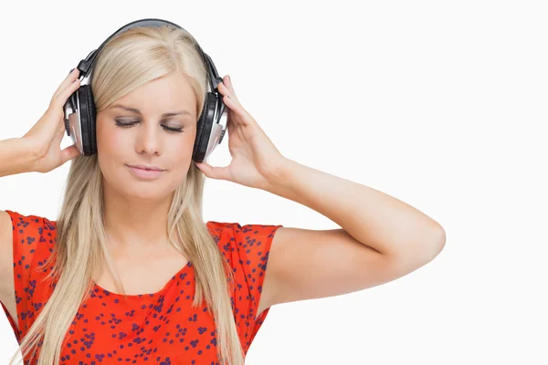 Blonde in orange dress listening to music — Stock Photo, Image