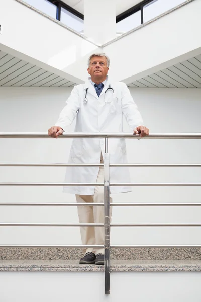 Thinking doctor stands at railing — Stock Photo, Image