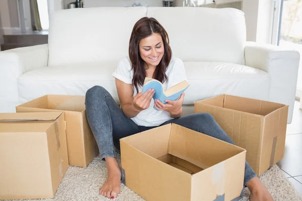 Woman looking at book from moving box — Stock Photo, Image