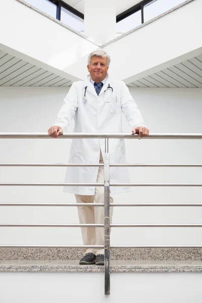 Smiling doctor leaning against rail — Stock Photo, Image