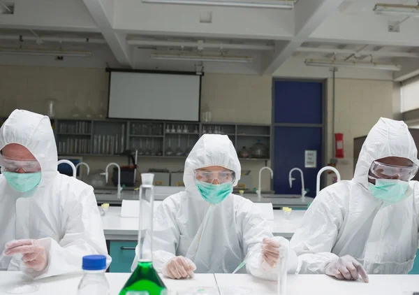 Chemists in protective suits adding liquid to petri dishes — Stock Photo, Image