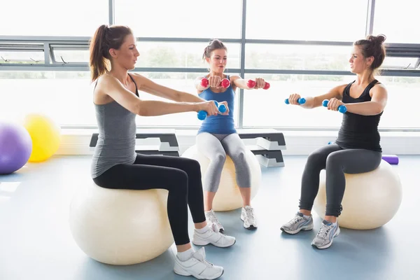 Drei Frauen stemmen gemeinsam Gewichte auf Gymnastikbällen — Stockfoto