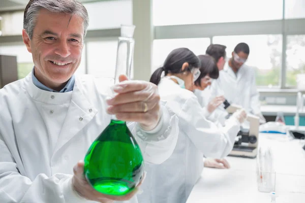 Chemist smiling and holding beaker — Stock Photo, Image