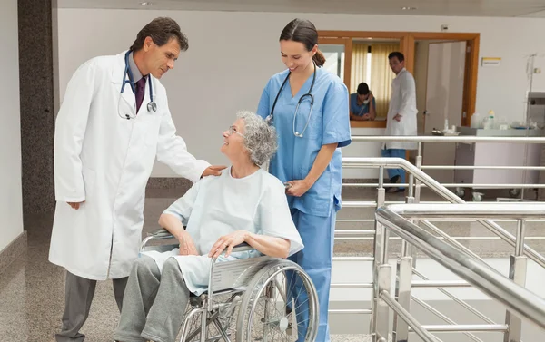 Verpleegster en arts praten met oude vrouw in rolstoel — Stockfoto