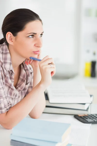 Mujer pensando mientras sostiene una pluma — Foto de Stock