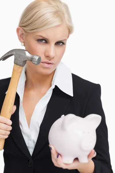 Mulher de negócios bonita segurando um martelo e um porquinho-banco — Fotografia de Stock