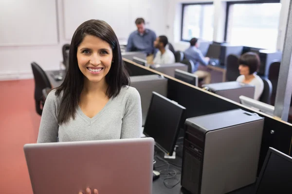 Mujer usando laptop mientras otros trabajan en computadoras — Foto de Stock