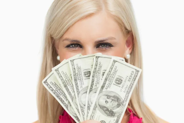 Loira sorridente escondendo seu rosto com notas de 100 dólares — Fotografia de Stock