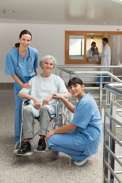 Duas enfermeiras com mulher idosa em cadeira de rodas — Fotografia de Stock
