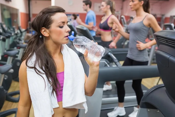 Woman drinking water beside treadmill — Stock Photo, Image