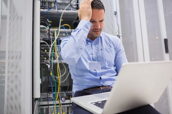 Man getting stressed with laptop over servers — Stock Photo, Image