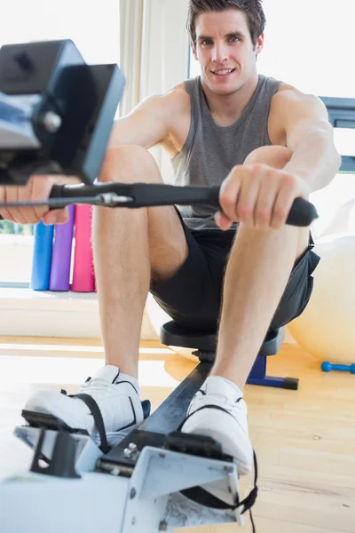 Hombre haciendo ejercicio en la máquina de fila — Foto de Stock