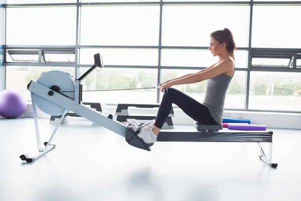 Mujer haciendo ejercicio en la máquina de fila — Foto de Stock