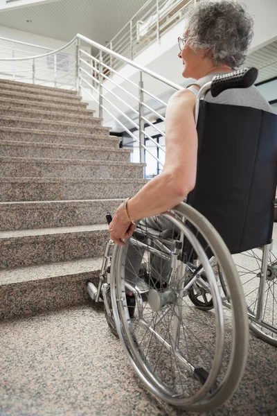 Elderly lady in wheelchair looking up stairs — Stock Photo, Image