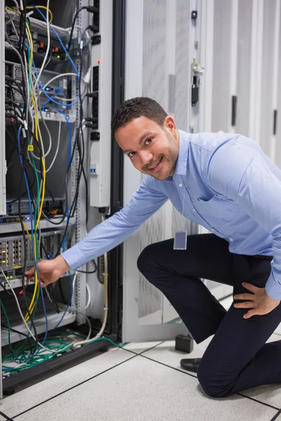 Sonriente hombre ajustando el cable en el servidor —  Fotos de Stock