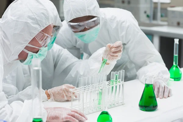 Two chemists experimenting with the green liquid — Stock Photo, Image