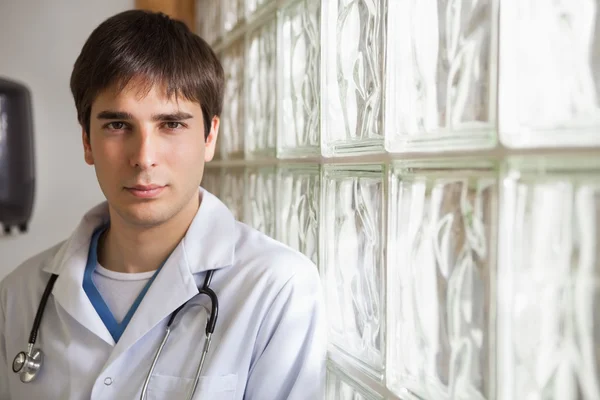 Doctor leans against glass wall — Stock Photo, Image