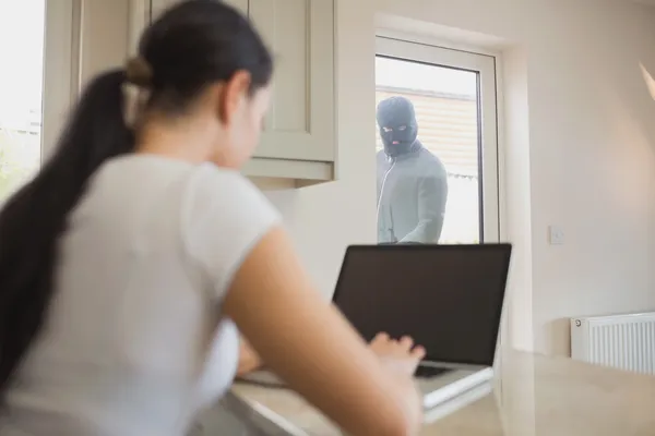 Грабитель смотрит на женщину через стеклянную дверь — стоковое фото