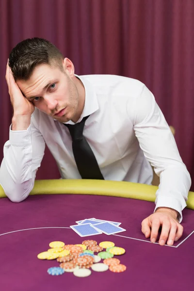 Чоловік дивиться нещасливий за покерним столом — стокове фото
