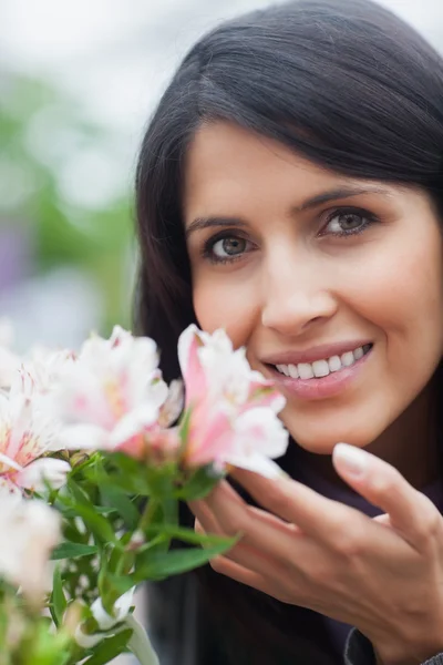 Mujer sonriente oliendo una flor — Foto de Stock