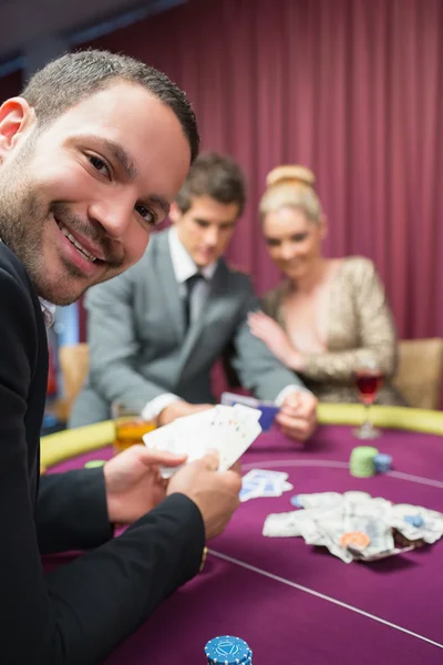 Muž s úsměvem při posezení u pokerového stolu — Stock fotografie